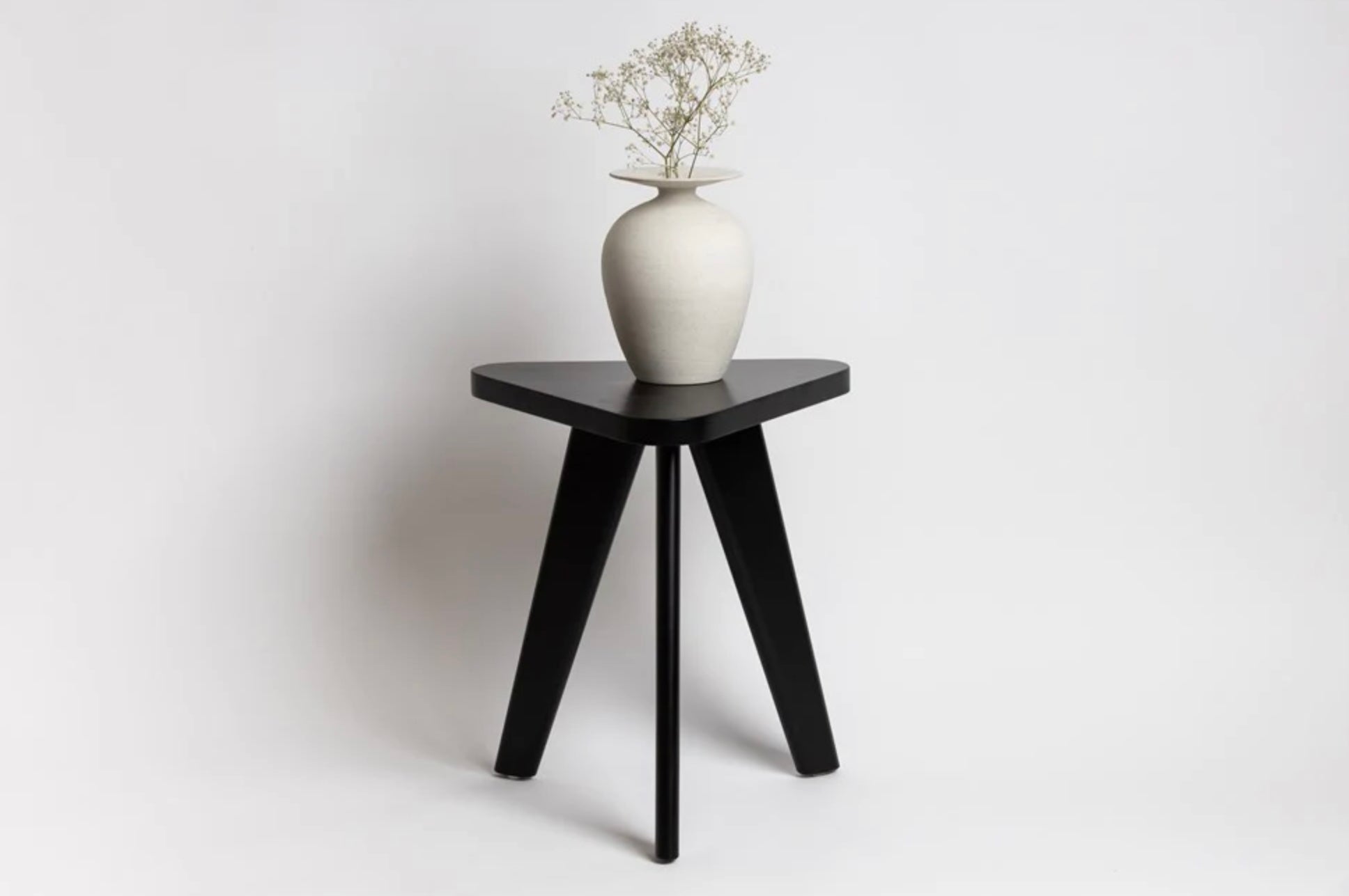 Chambers Design's KWH Side Table is a modern side table option for the home or office. It is a one-of-a-kind and stylish occasional table made of solid Beech wood, with graduated legs and a rounded triangular top.