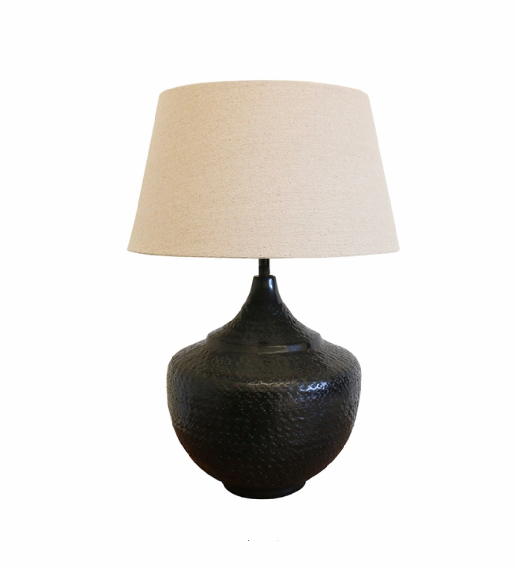 The Sarajavo lamp base, in a textured metal Iron Urn style lamp in a black/bronze finish, with an oatmeal fabric shade from Chambers Design.