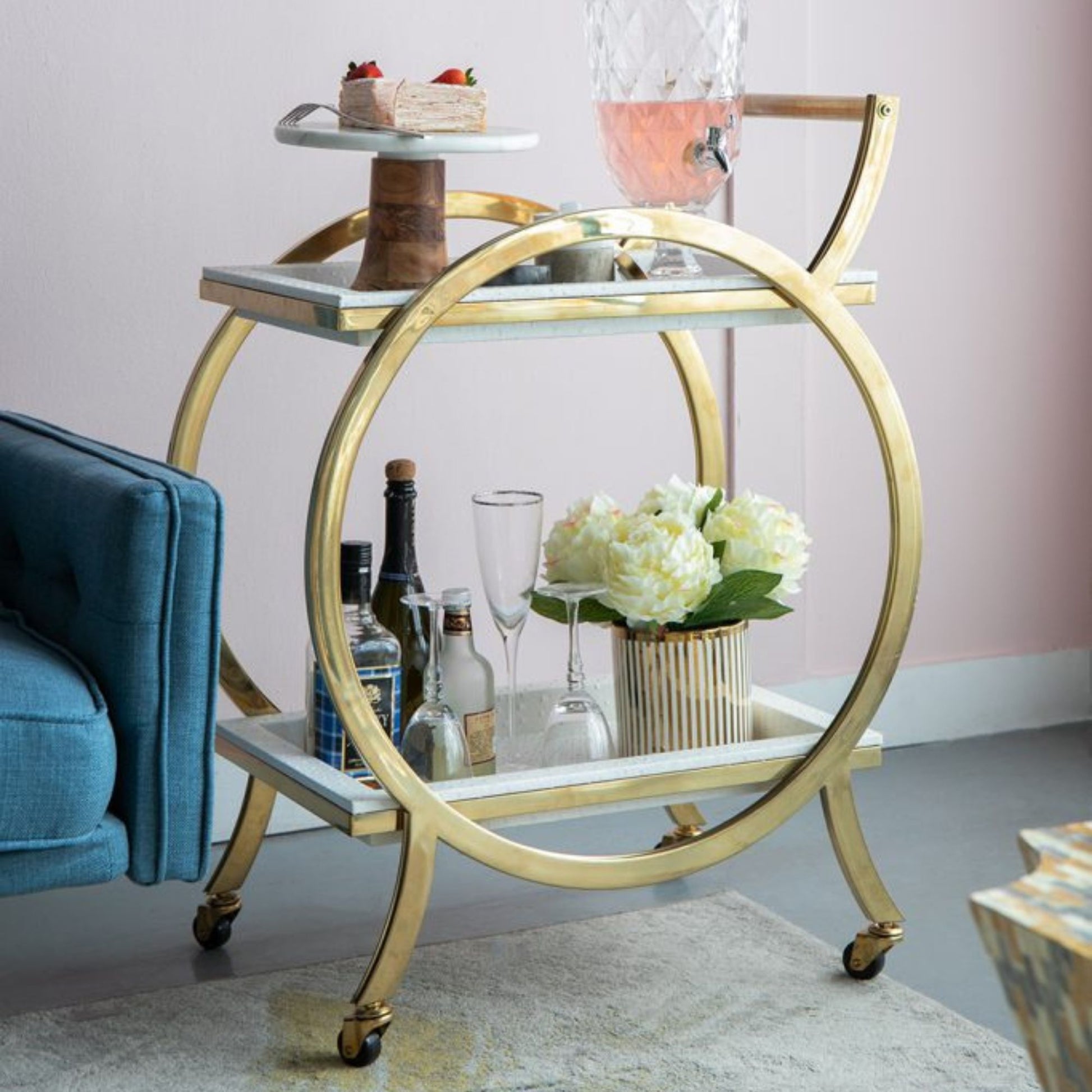 This cart features a circular frame design in stainless steel with a gleaming gold finish and two removable serving trays. Complete with a handle and casters for mobility, this gorgeous contemporary entertainer was designed for both form and functionality